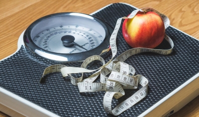 Measuring tape and apple on scale